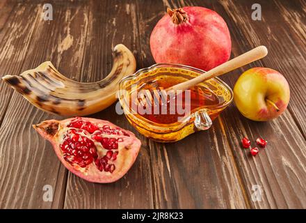 Rosh hashanah - concetto ebraico di vacanza di nuovo anno. Ciotola a forma di mela con miele, mele, melograni, shofar su fondo di legno d'annata Foto Stock