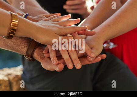 Un patto per rimanere amici per sempre. Un gruppo di amici non identificabili mette le mani in un mucchio a una festa all'aperto. Foto Stock