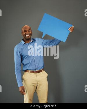 Sorridente, afroamericano maschio elettore in possesso di un cartello copyspace su messaggio di opinione pubblica. Uomo casuale e positivo che tiene un discorso sui social media Foto Stock