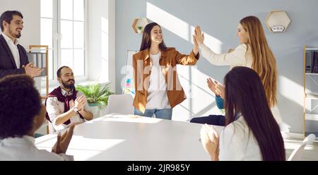 I colleghi si assegnano a vicenda cinque persone di alto livello durante la riunione aziendale per celebrare i risultati di successo. Foto Stock