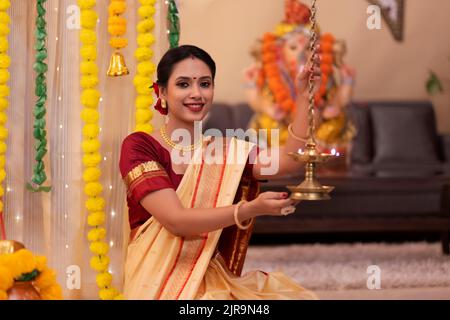 Ritratto di donna Maharashtria in abito tradizionale con lampada ad olio in occasione di Ganesh Chaturthi Foto Stock