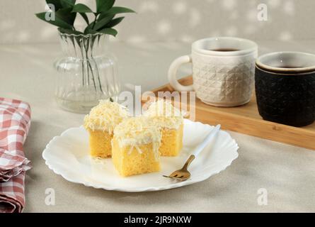 Fetta di formaggio, torta di spugna fatta in casa con formaggio grattugiato sulla parte superiore. Servito con tè Foto Stock