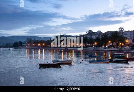 Tramonto sul lungomare di San Vicente de la Barquera in Cantabria (Spagna), con le luci che si riflettono nel mare della Cantabria Foto Stock