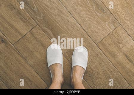 Piedi maschili e ciabatte bianche monouso in camera d'hotel, vista dall'alto  Foto stock - Alamy