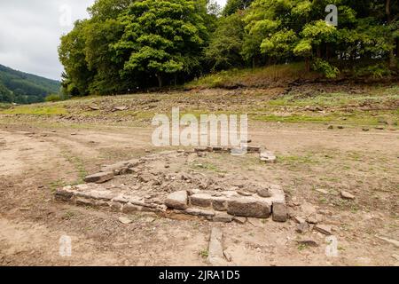 La foto mostra il sito del villaggio perduto che ora può essere visto. Il serbatoio di Ladybower durante il tempo secco e la siccità nell'estate del 2022. Ladybower Reservoir è un grande serbatoio artificiale a forma di Y, il più basso dei tre nella Upper Derwent Valley nel Derbyshire, Inghilterra. Foto Stock