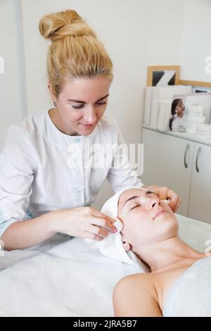 Il cosmetologo pulisce la pelle di un cliente di un salone di bellezza prima della procedura e del massaggio facciale. Concetto di gioventù e salute Foto Stock