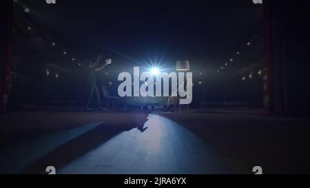 Un'attrice teatrale con disabilità che esce dal sipario su un palcoscenico oscurato in una sedia a rotelle al teatro con riflettore, durante una prova di un gioco con cast d'azione Foto Stock