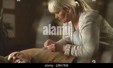 Vista inclinata verso il basso della donna anziana che dà tablet e toccare la fronte di un anziano malato che soffre di mal di febbre sul divano a casa Foto Stock