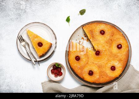 Torta di ananas capovolta tagliata a fette con ciliegie candite e caramello. Dessert tropicale estivo. Vista dall'alto. Foto Stock
