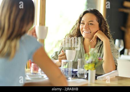 Due donne che parlano e bevono caffè seduti in un ristorante Foto Stock