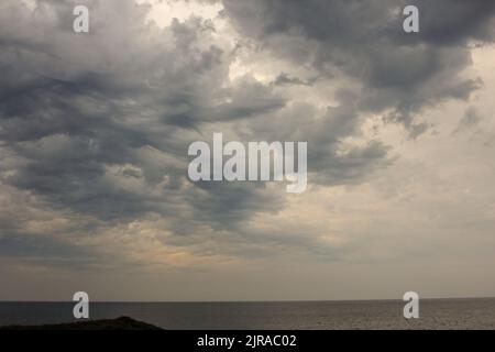 durante il tramonto si formano delle nuvole drammatiche sul mare Foto Stock