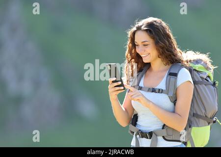 Felice escursionista di consulenza smartphone durante il trekking in montagna Foto Stock