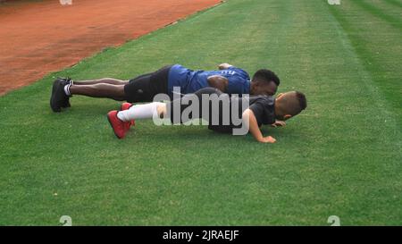 Fai un giro per vedere il coach nero e il ragazzo da corsa misto in abbigliamento sportivo che fa salire in campo durante gli allenamenti di calcio allo stadio Foto Stock