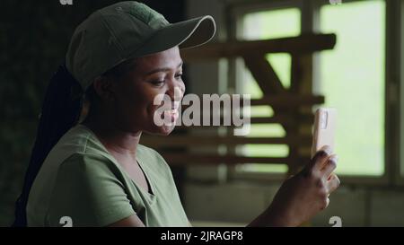 Felice soldato afro-americano che agita la mano e sorride mentre videochiama un amico su smartphone Foto Stock