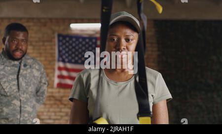 Soldato afro-americano che respira e ascolta l'istruttore maschile durante la pausa in sospensione allenamento in palestra della base militare degli Stati Uniti Foto Stock