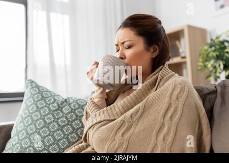donna asiatica malata che beve tè caldo a casa Foto Stock