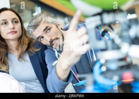 Tecnici che mostrano il nuovo robot industriale a un collega senior Foto Stock