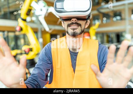 Lavoratore industriale in fabbrica di robotica che utilizza un simulatore di realtà virtuale Foto Stock