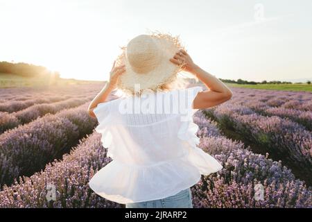 Donna che indossa cappello di paglia in piedi in campo di lavanda Foto Stock