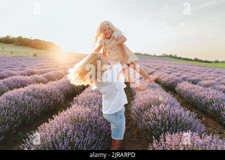 Mamma gioiosa godendosi con la figlia in campo di lavanda Foto Stock