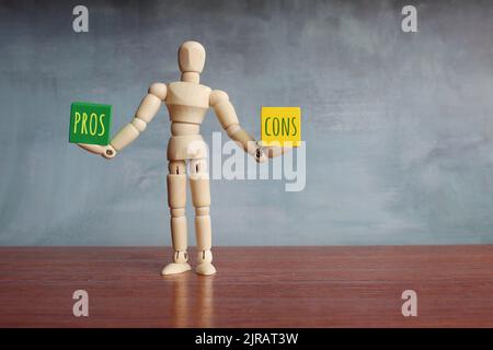 Concetto di equilibrio pro e contro. Figura umana in legno che bilancia cubi in legno con TESTI PRO e CONS. Copia spazio per il testo Foto Stock