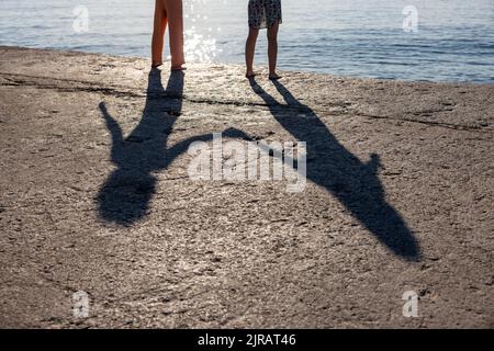 Ombra di coppia che tiene le mani in piedi sul molo Foto Stock