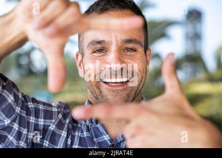 Uomo maturo felice che fa la cornice del dito Foto Stock