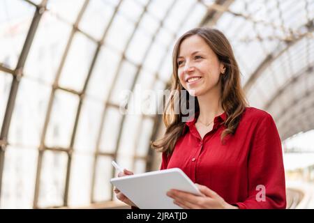Donna sorridente che tiene un tablet PC Foto Stock