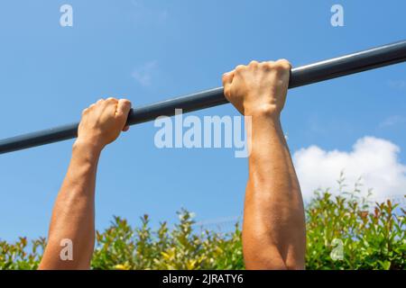 Le mani si tengono sul bar orizzontale sulla strada, area di allenamento all'aperto Foto Stock