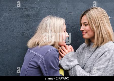 Donna anziana sorridente che tiene le mani di figlia Foto Stock