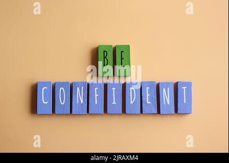 Vista dall'alto immagine di cubi di legno con testo ESSERE SICURI. Motivazione e concetto di ispirazione. Foto Stock