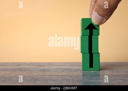 Concetto di impostazione degli obiettivi. Disporre a mano i cubetti di legno con l'icona della freccia rivolta verso l'alto. Copia spazio per il testo. Foto Stock