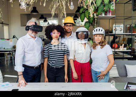 Colleghi di lavoro multirazziali che indossano occhiali e caschi diversi in ufficio Foto Stock