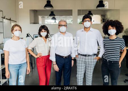 Colleghi d'affari che indossano una maschera protettiva sul posto di lavoro Foto Stock