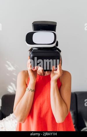 Donna che indossa cuffie per realtà virtuale a casa Foto Stock