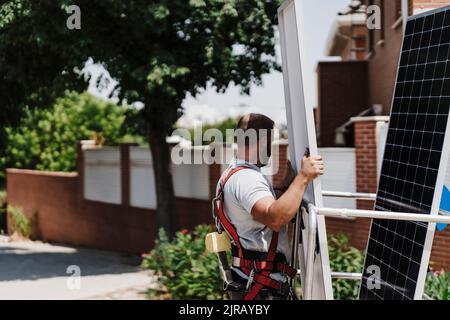 Artigiano che carica pannello solare in piattaforma idraulica nella giornata di sole Foto Stock