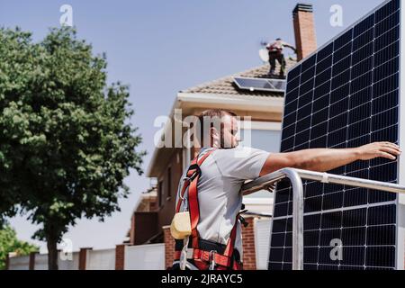 Ingegnere che carica pannello solare in piattaforma idraulica Foto Stock