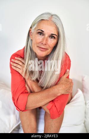 Sorridente donna matura seduti sul divano Foto Stock