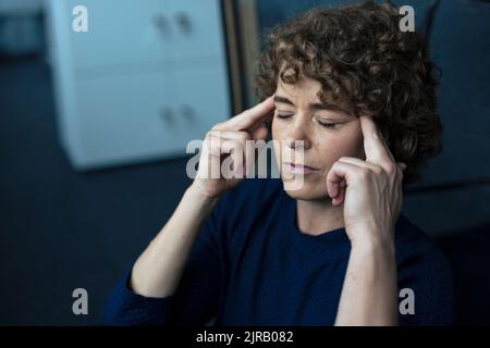 Donna d'affari stressata seduta con gli occhi chiusi Foto Stock