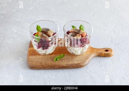 salmone affumicato, barbabietola e insalata di formaggio morbido servita in due bicchieri e decorata con foglie di basilico Foto Stock