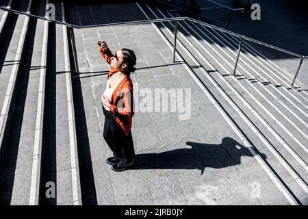 Donna d'affari che protegge gli occhi dalla luce del sole sulle scale Foto Stock