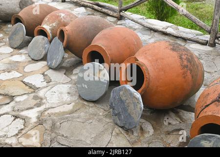 Fila di tradizionali vasi georgiani in argilla kvevri con coperture in pietra Foto Stock