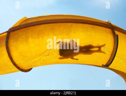 Silhouette di due persone che scivolano giù scivolo d'acqua Foto Stock