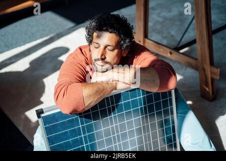 Uomo d'affari con pannello solare sotto la luce del sole in ufficio Foto Stock