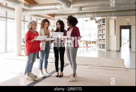 Donna d'affari che discute sui documenti con i colleghi in ufficio Foto Stock