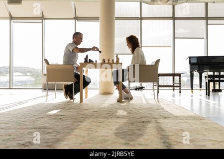 Donna d'affari matura che gioca a scacchi con un giovane collega in ufficio Foto Stock