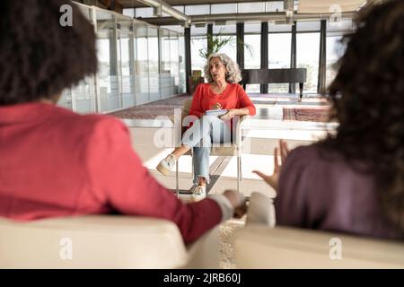 Donna d'affari senior che condivide idee con i colleghi in ufficio Foto Stock