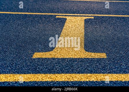 Primo piano la lettera, iniziale i su una nuova pista blu con linee di corsia gialle. Foto Stock