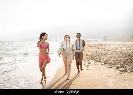 Donne multirazziali che camminano in spiaggia nelle giornate di sole Foto Stock