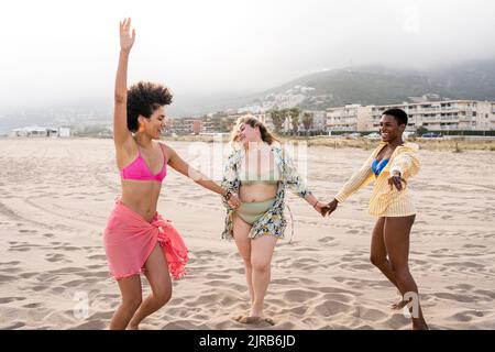 Donne multirazziali che ballano in spiaggia Foto Stock